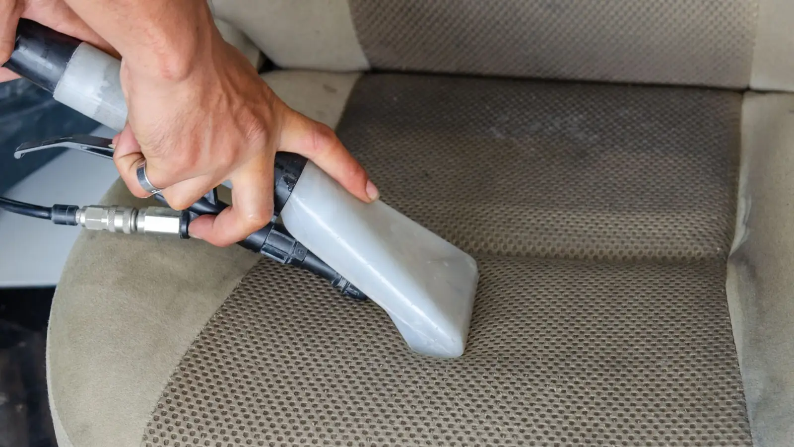 Upholstery extractor cleaning a cloth car seat