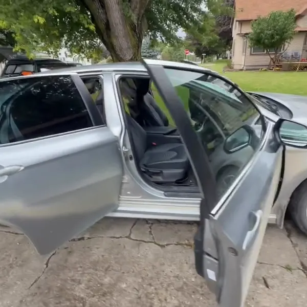 Silver car with its doors open in a customer's driveway during a mobile detail